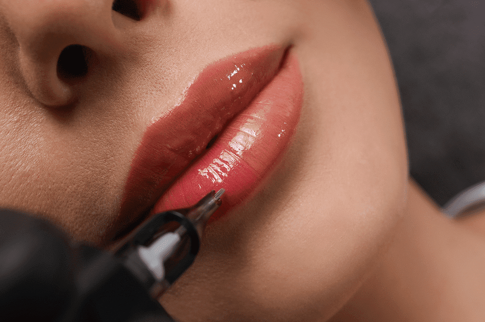 Close-up of a person receiving lip tattooing cosmetic treatment with a needle.